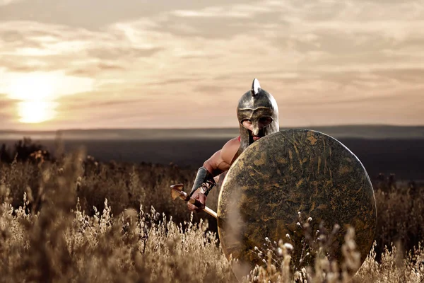 Soldado como espartano em capacete de bronze segurando escudo arredondado . — Fotografia de Stock