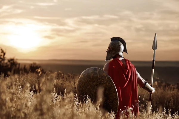 Warrior wearing iron helmet and red cloak. Royalty Free Stock Images