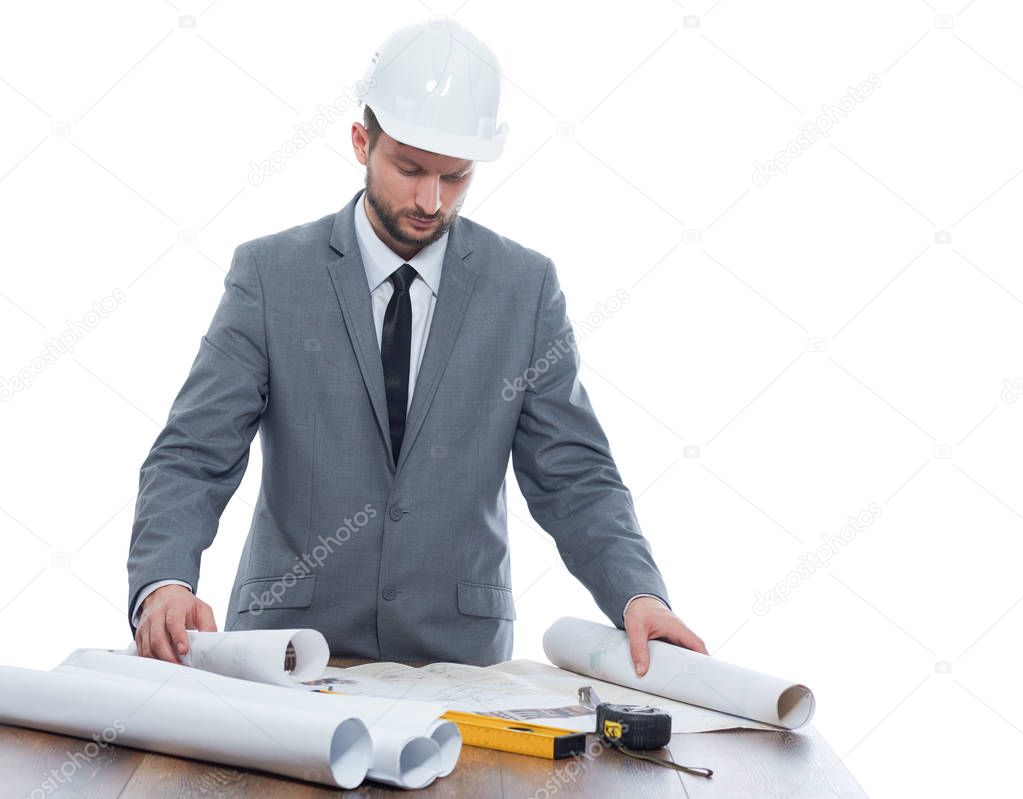 Architect at work place reading plan of building.