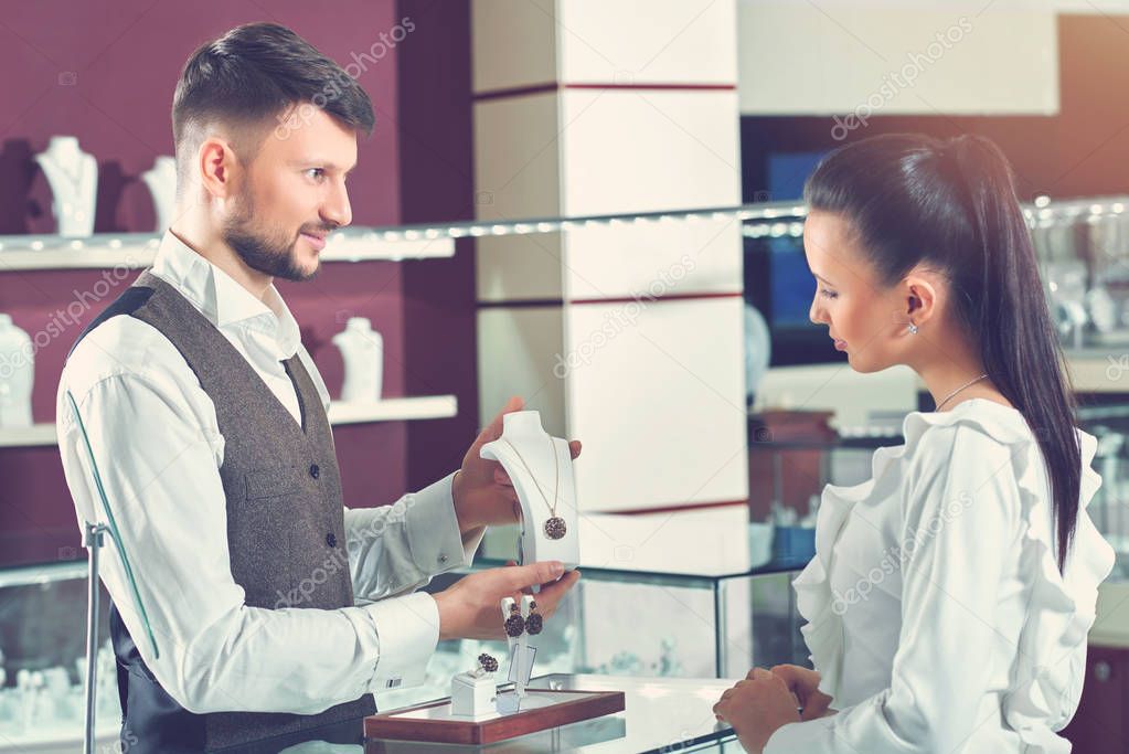 Professional male jeweler helping his female customer at the sto