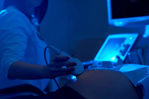 筛查孕妇在黑暗的医生使用超声和凝胶. — 图库照片