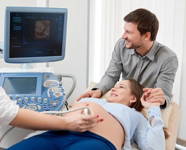 Férje támogató terhes feleségét aki diagnosting Klinika. — Stock Fotó