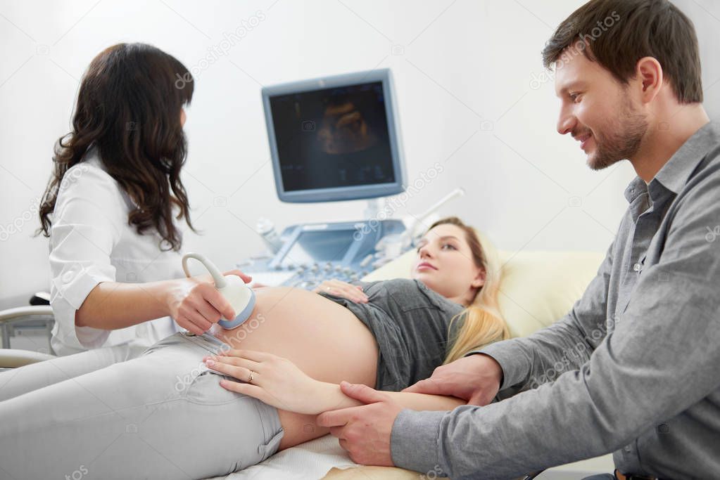 Husband holding pregnant wife by hand diagnosed ultrasound.
