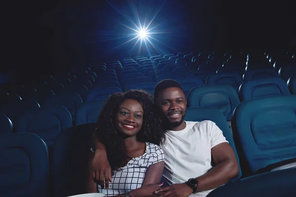 Positive couple of africans watching movie in cinema.