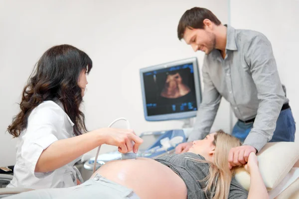 Marido cuidando sobre embarazada esposa en procedimiento de ultrasonido . — Foto de Stock