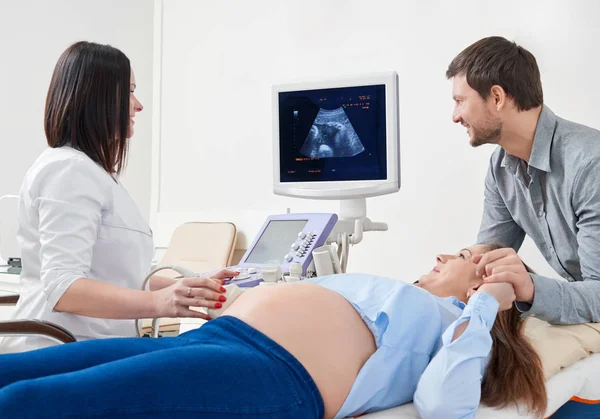 Marido que transporta sobre a esposa no procedimento de ultrassom na clínica . — Fotografia de Stock