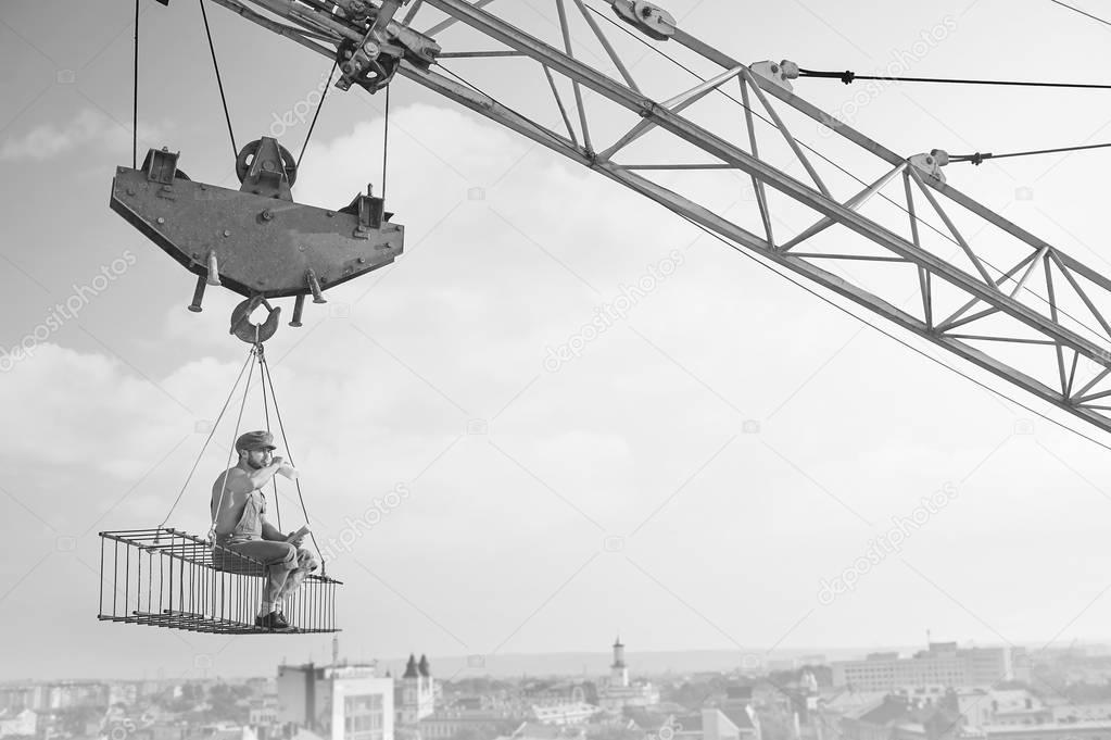 Vintage handyman having lunch on a crossbar hanging above the ci