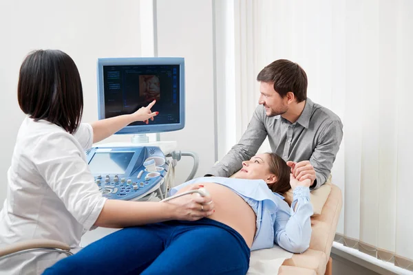 Médico apuntando a la pantalla del bebé en el estómago de la madre embarazada . — Foto de Stock