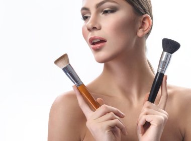Makyaj fırçaları beyaz izole tutan güzel genç kadın
