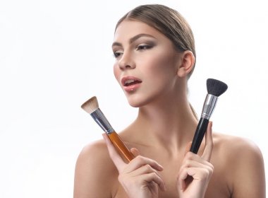 Makyaj fırçaları beyaz izole tutan güzel genç kadın