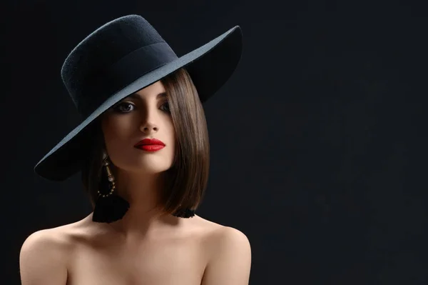 Mujer atractiva con un sombrero posando sobre fondo negro — Foto de Stock