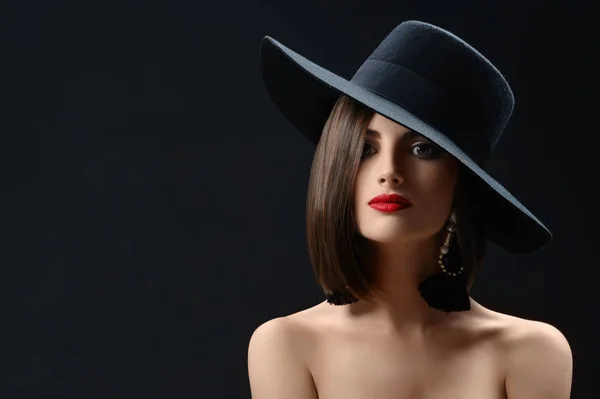 Mujer atractiva con un sombrero posando sobre fondo negro — Foto de Stock