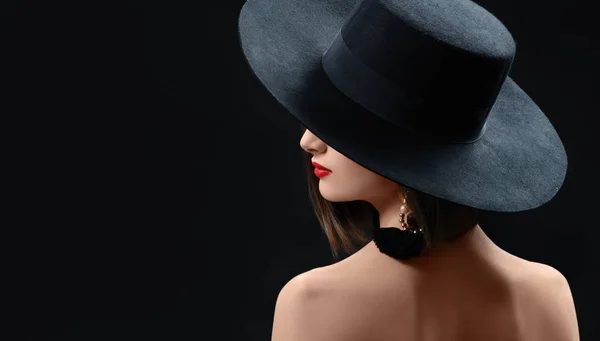 Mujer atractiva con un sombrero posando sobre fondo negro — Foto de Stock