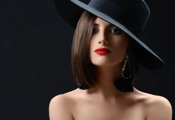 Привлекательная женщина в шляпе позирует на черном фоне — стоковое фото