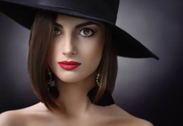 Mujer atractiva con un sombrero posando sobre fondo negro — Foto de Stock