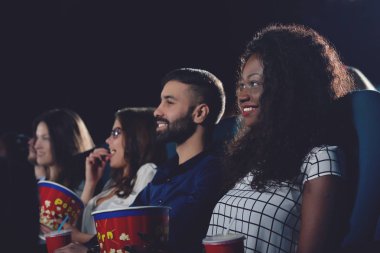 Kıvırcık Afrikalı kız dişlek gülümseyen ve sinema filmi izlerken.