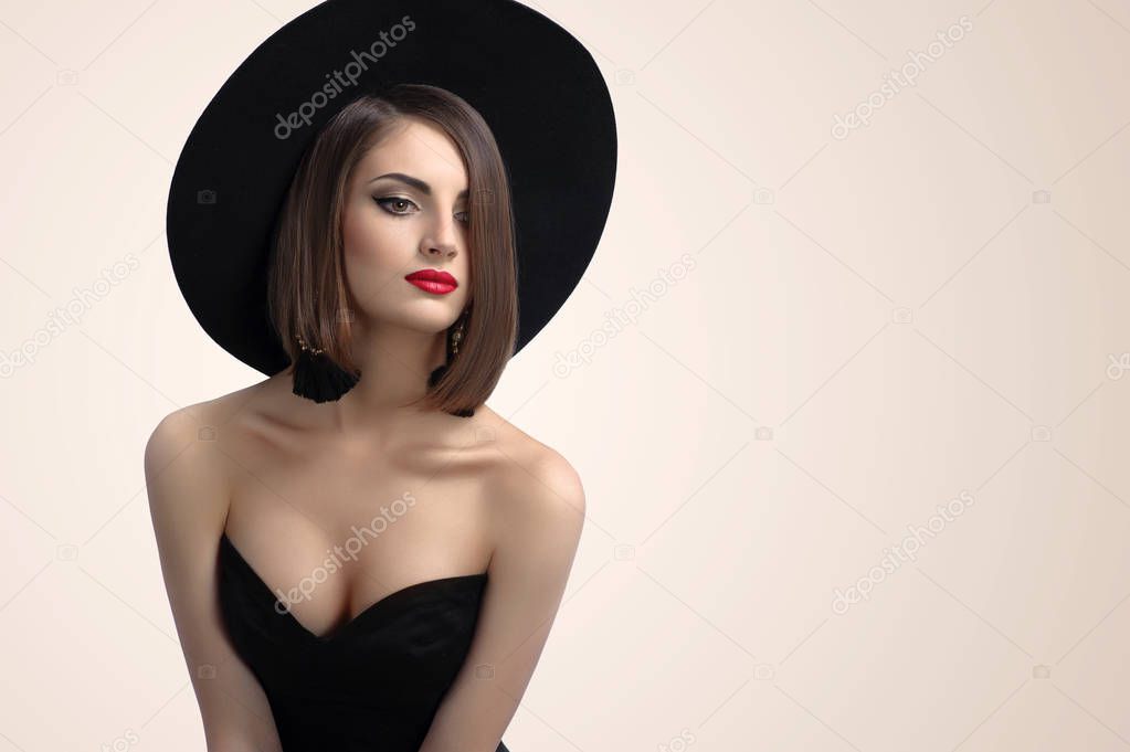 Elegant fashionable woman posing wearing a hat in studio