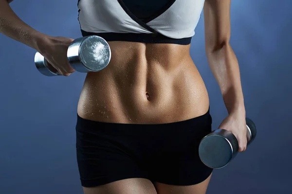 Mujer usando equipo de entrenamiento sosteniendo pesas — Foto de Stock