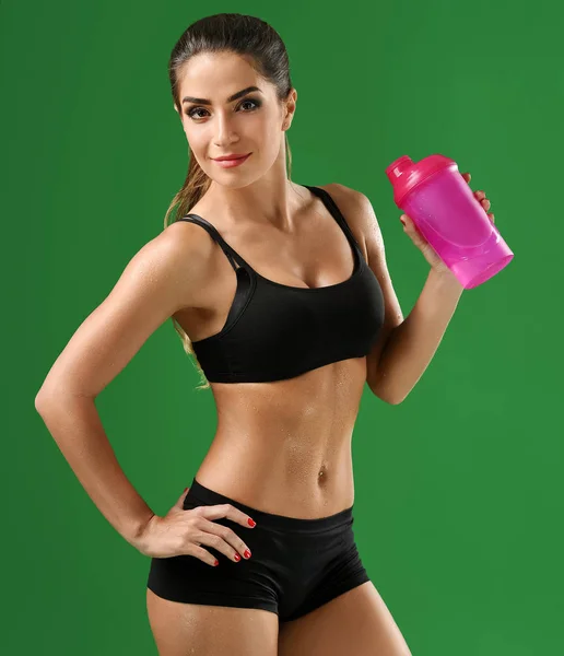 Attraktive junge Fitness-Frau mit Sportflasche auf grünem Bac — Stockfoto