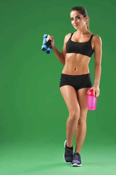 Attraktive junge Fitness-Frau mit Sportflasche auf grünem Bac — Stockfoto