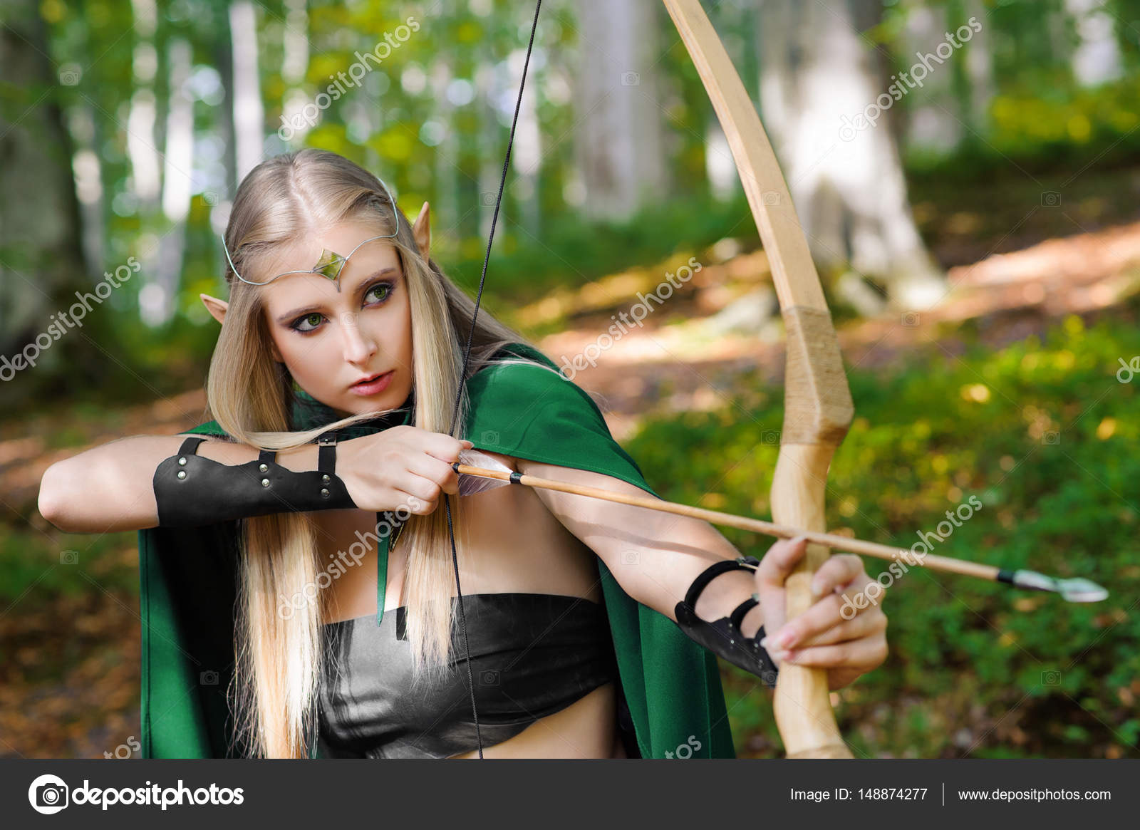Beautiful female elf archer in the forest hunting with a bow Stock