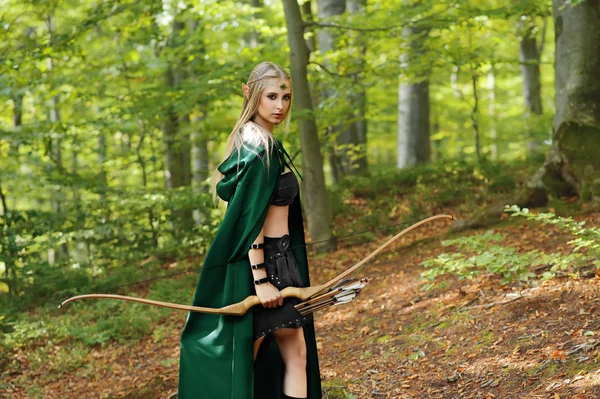 Bela fêmea elfo arqueiro na floresta caça com um arco — Fotografia de Stock