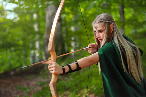 Beautiful female elf archer in the forest hunting with a bow