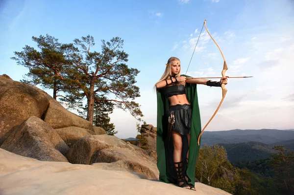 Hermosa hembra arquero elfo en la caza del bosque con un arco —  Fotos de Stock
