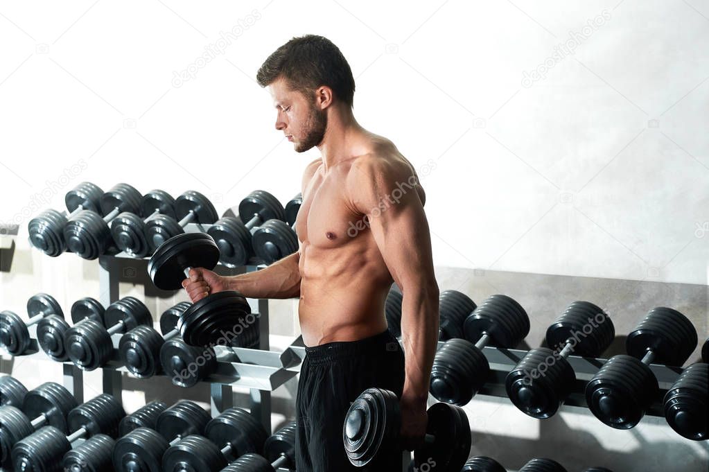 Handsome young athlete working out at the gym
