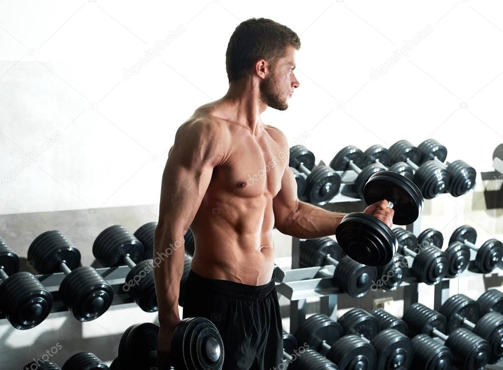 Handsome young athlete working out at the gym