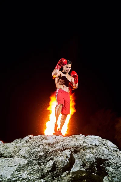 拳击冠军与火燃烧在合影在岩石上 — 图库照片