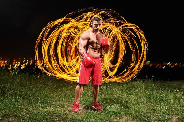 Fuerte luchador masculino muscular con fuego y llamas detrás de su bac — Foto de Stock