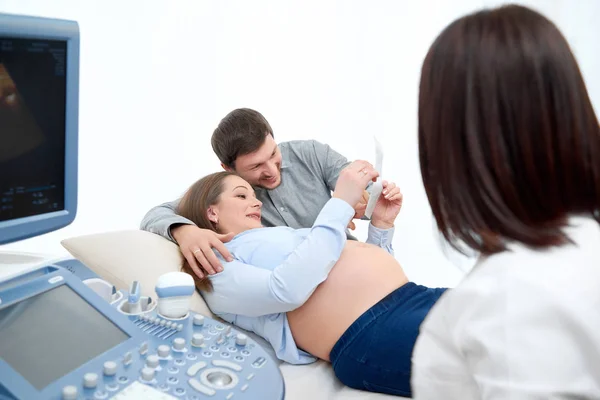 Jovem amando casal grávida visitando médico juntos — Fotografia de Stock