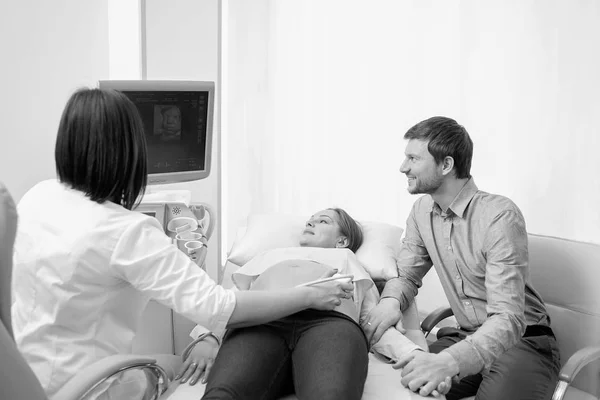 Young loving pregnant couple visiting doctor together monochrome