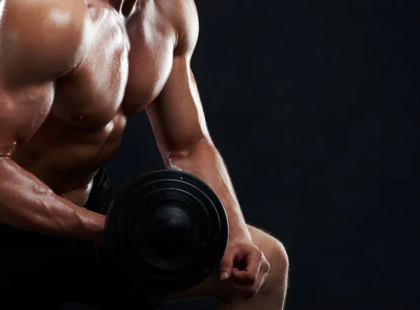 Muscular young man lifting weights on black background — Stock Photo, Image