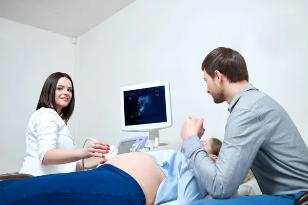 Молода любляча вагітна пара відвідує лікаря разом — стокове фото
