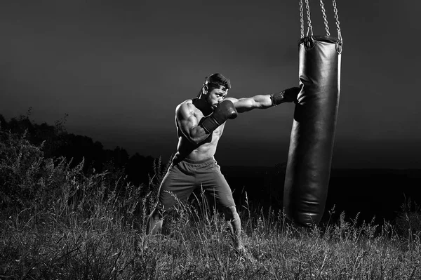 Monochrome shots of a male boxer training with a punching bag ou