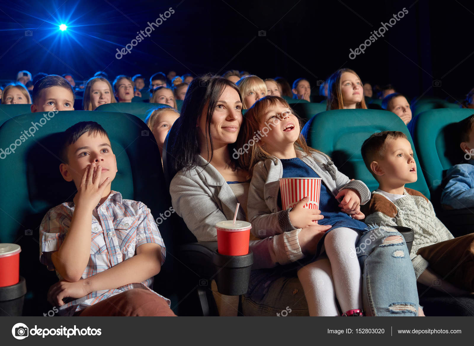 Children with parents enjoying a movie together at the cinema Stock