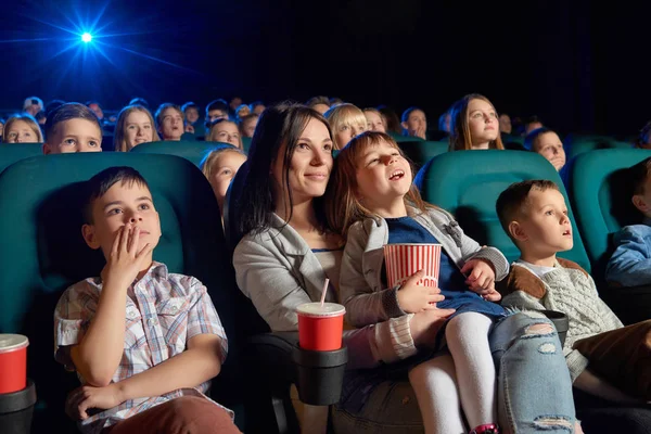 Barn med foreldre som nyter en film sammen på kino stockbilde