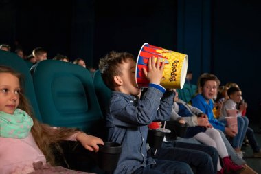 Küçük çocuk sinemada patlamış mısır yemek