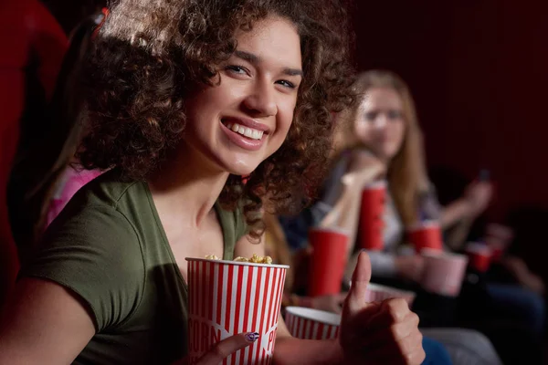 Beautiful smiling woman with volumed curly hair at cinema hall. — Stock Photo, Image