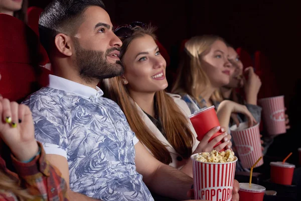 Beautiful couple watching interesting film at cinema and smiling. — Stock Photo, Image