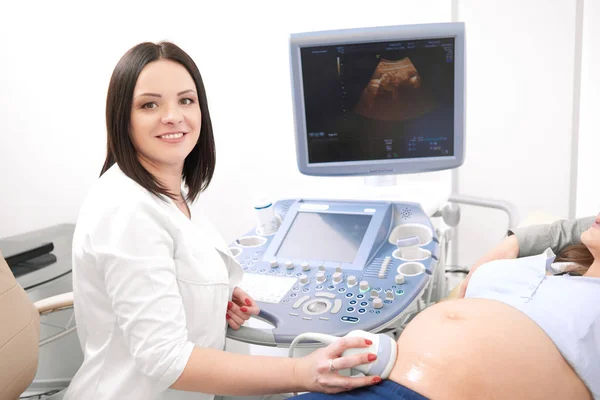 Профессиональный врач проверяет беременную женщину и улыбается . — стоковое фото