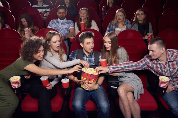 Друзі тягнуть руки до попкорну одного шокованого хлопчика в центрі . — стокове фото