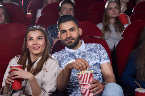 Аравійська чоловік і кавказька жінка їдять попкорн в кіно. — стокове фото