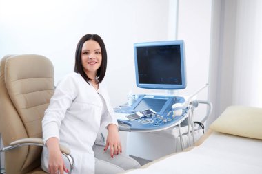 Profesyonel kadın doktor ultrason cihazları karşı oturan.