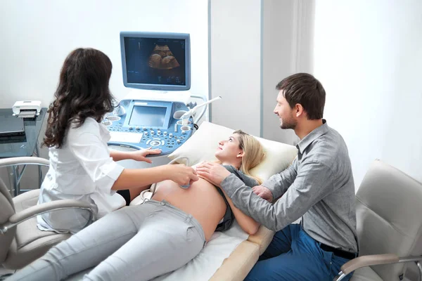 Marido transportando sobre esposa grávida no procedimento de ultrassom . — Fotografia de Stock