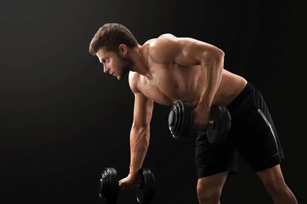 Muscular young man exercising with dumbbells — Stock Photo, Image