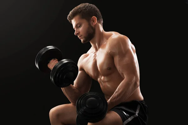 Muscoloso giovane uomo che si esercita con i manubri — Foto Stock