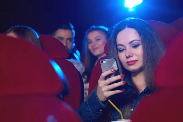 Young woman using smart phone at the cinema